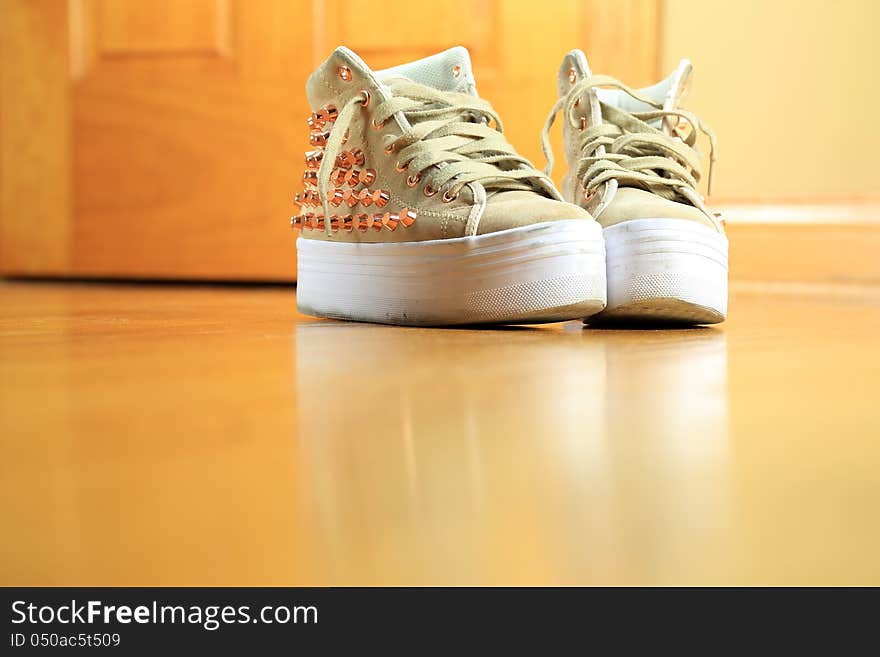 A pair of funky used sneaker shoes with studs on hard wood floor. A pair of funky used sneaker shoes with studs on hard wood floor