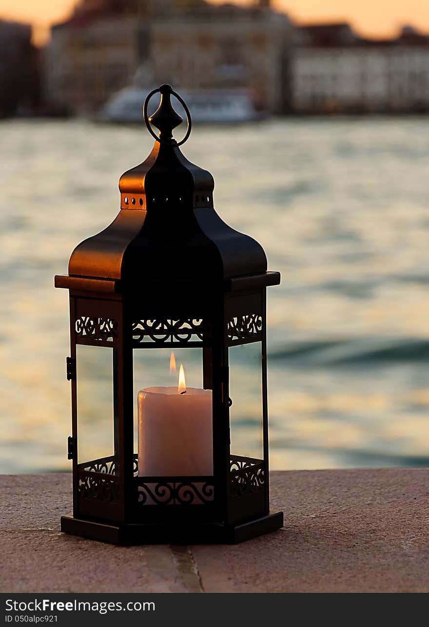 burning lantern. Sea and buildings on background