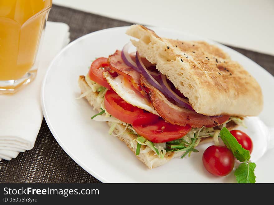 Healthy bacon and egg burger with onions, tomatoes and lettuce on turkish bread.