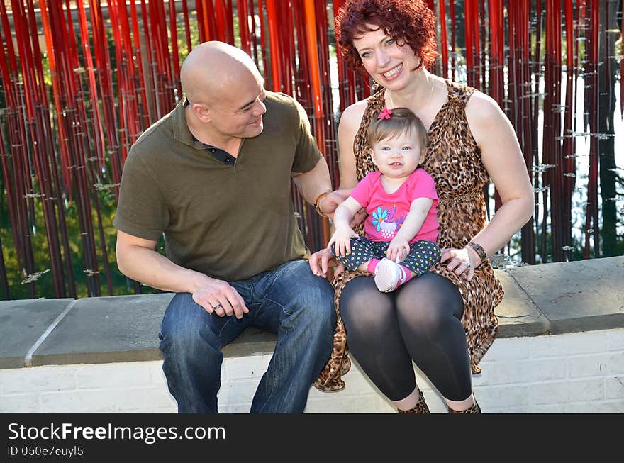 Diverse family portrait of an Asian men and white women with their baby girl. Beautiful multiracial family. Happy family at a park interacting.