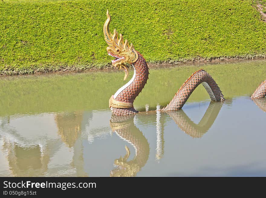 Naga statue. Swamp temple in green grass.