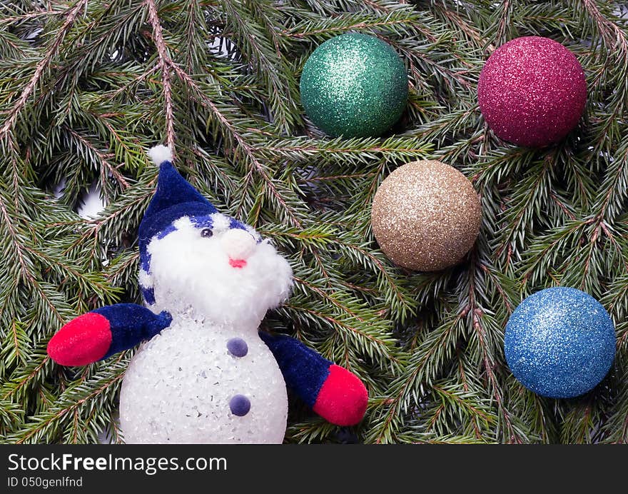 Colorful balls and snowman lying on spruce branches. background