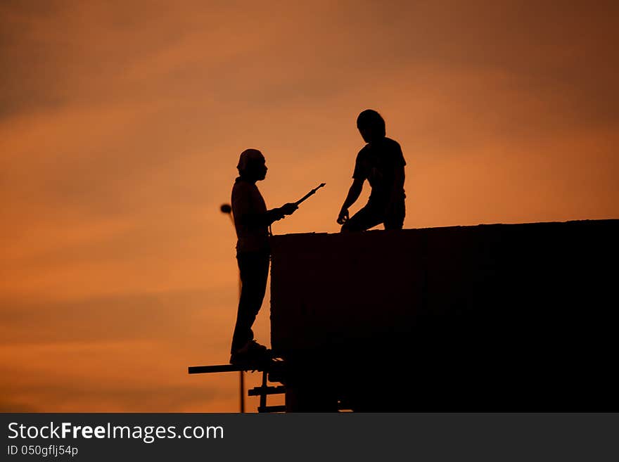 Silhouettes of worker welder at sunset