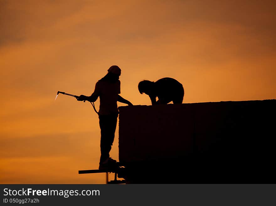 Silhouettes of worker welder at sunset