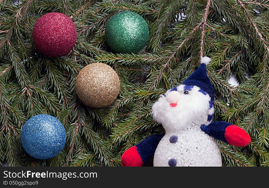 Colorful balls and snowman lying on spruce branches.