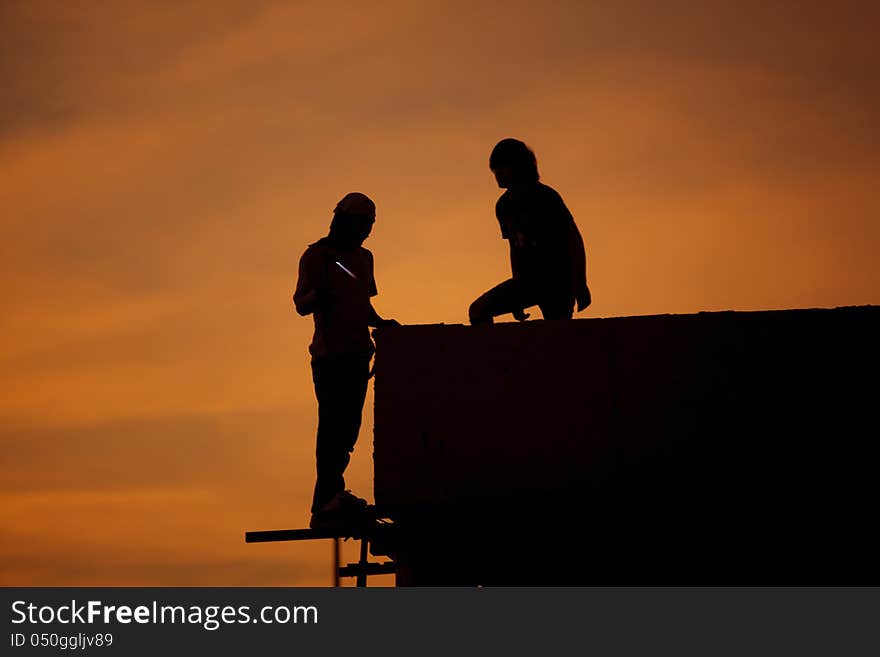 Silhouettes of worker welder at sunset