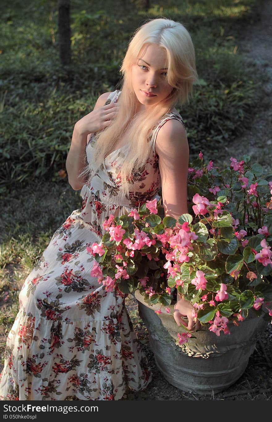 An image of a pretty woman sitting outside surrounded by greenery. An image of a pretty woman sitting outside surrounded by greenery