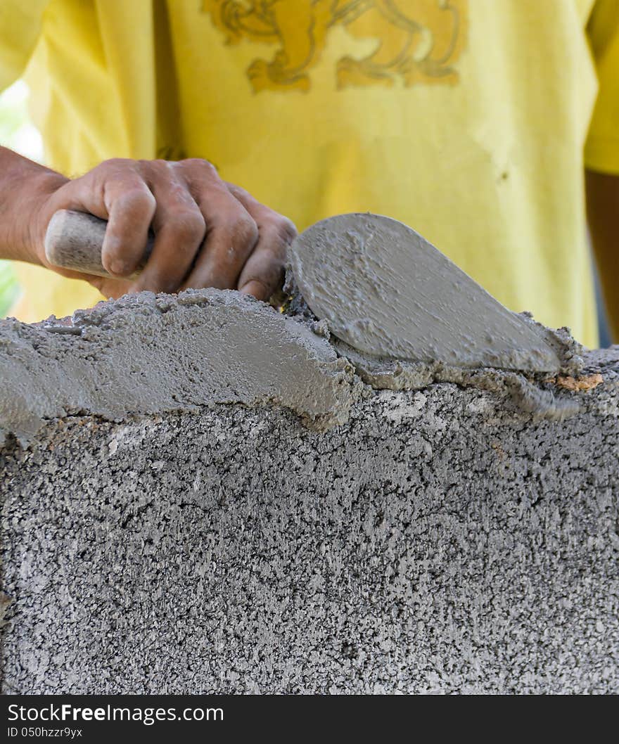 Bricklayer putting down another row of bricks in site