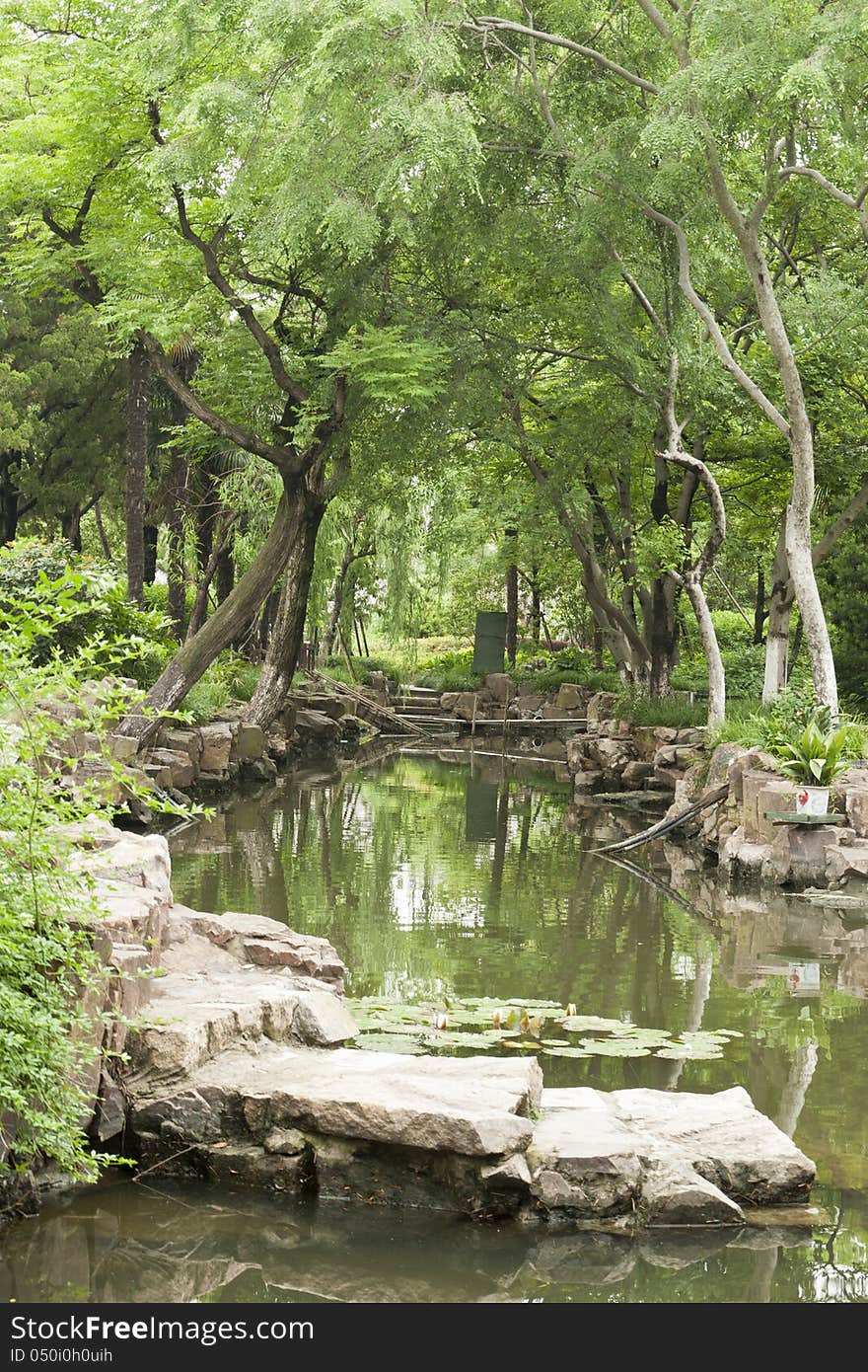 A tree-covered stream in a chinese traditional garden