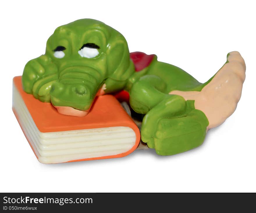 The photo shows a baby toy souvenir. The ceramic green crocodile, which lies on the book. The photo shows a baby toy souvenir. The ceramic green crocodile, which lies on the book.