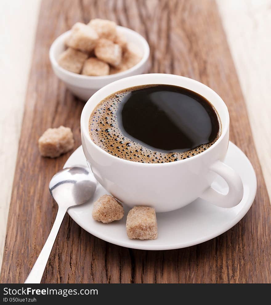 Cup of coffee with brown sugar on a wooden table. Cup of coffee with brown sugar on a wooden table.