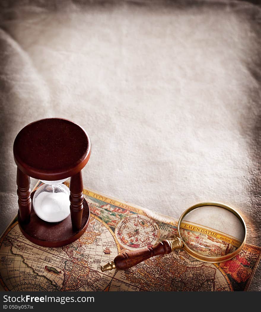 Hourglass with a magnifying glass on old parchment. Hourglass with a magnifying glass on old parchment.