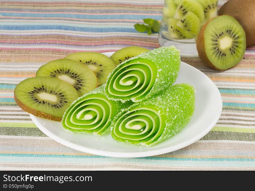 Green candy fruit on a plate with kiwi, closeup