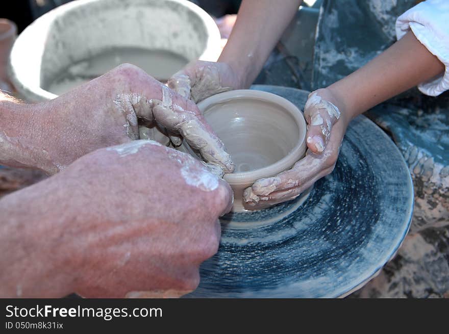 Hand of the potter and the child in the creation of new products from clay. Hand of the potter and the child in the creation of new products from clay