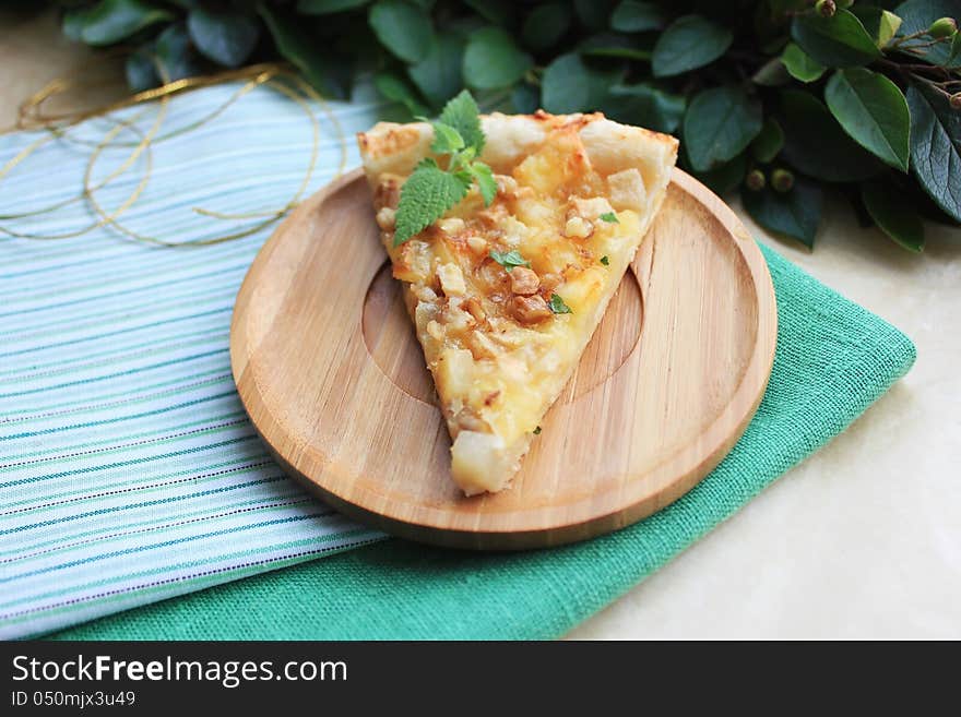 Puff pastry pie with pears and camembert cheese with walnuts and mint on a wooden plate