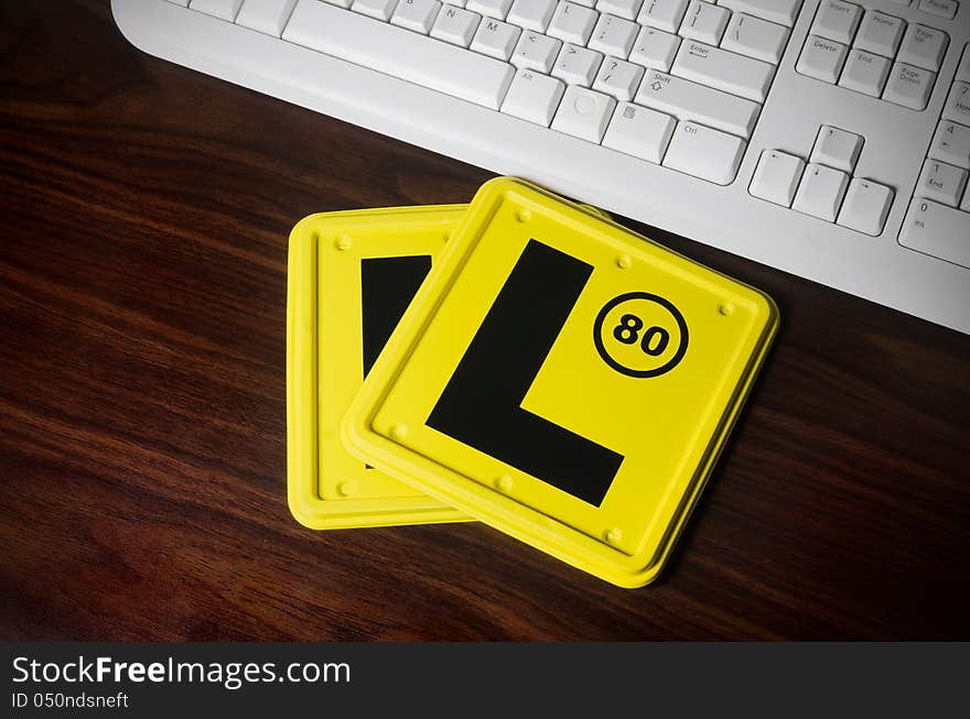 Two L plates laying on the computer desk next to the white keyboard.