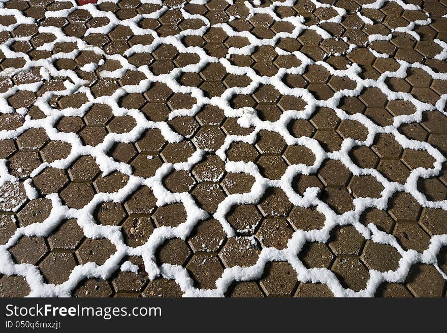 Hexagonal paving slabs covered with snow snaking line. Hexagonal paving slabs covered with snow snaking line