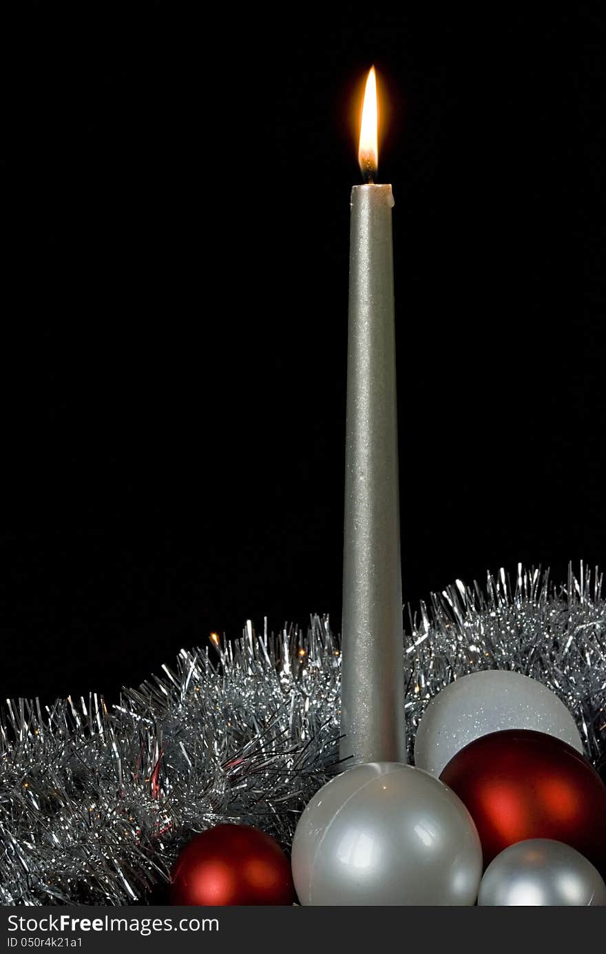 Burning silver candle and christmas balls on a black background. Burning silver candle and christmas balls on a black background