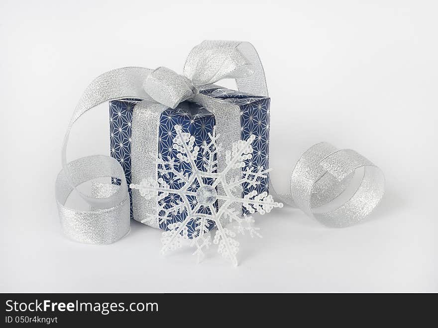 Gift box with silver ribbon and snowflake on a white background. Gift box with silver ribbon and snowflake on a white background