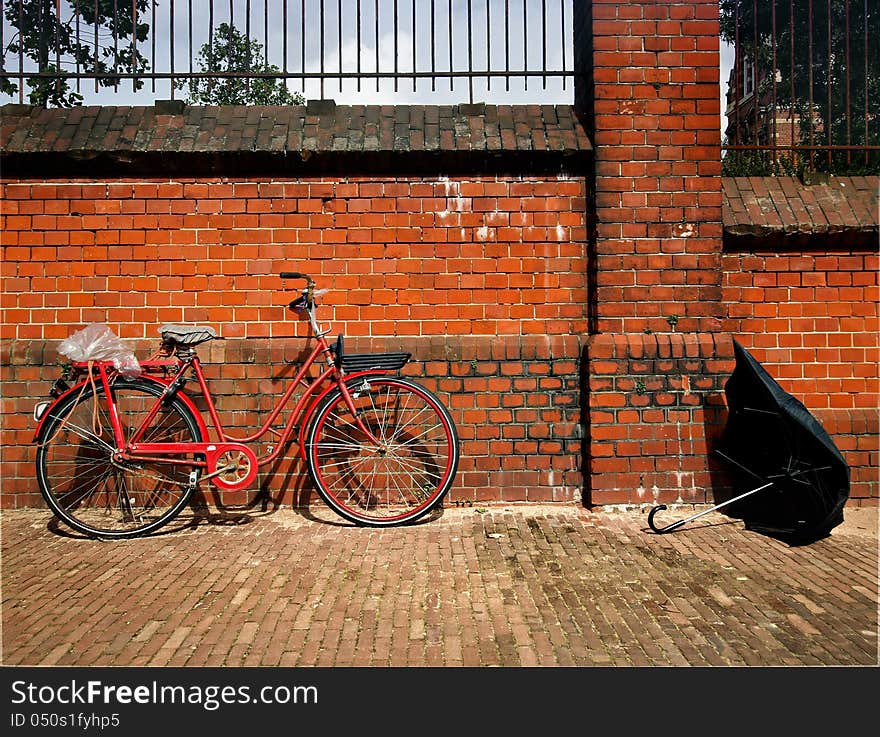 Old bicycle against brick wall with a broken umbrella few minutes after the rain passed