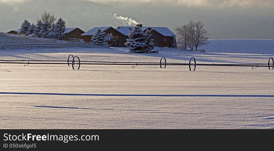 This image of the farm with smoke coming from the chimney, irrigation pipes and shadows in the new fallen snow was taken in NW Montana. This image of the farm with smoke coming from the chimney, irrigation pipes and shadows in the new fallen snow was taken in NW Montana.