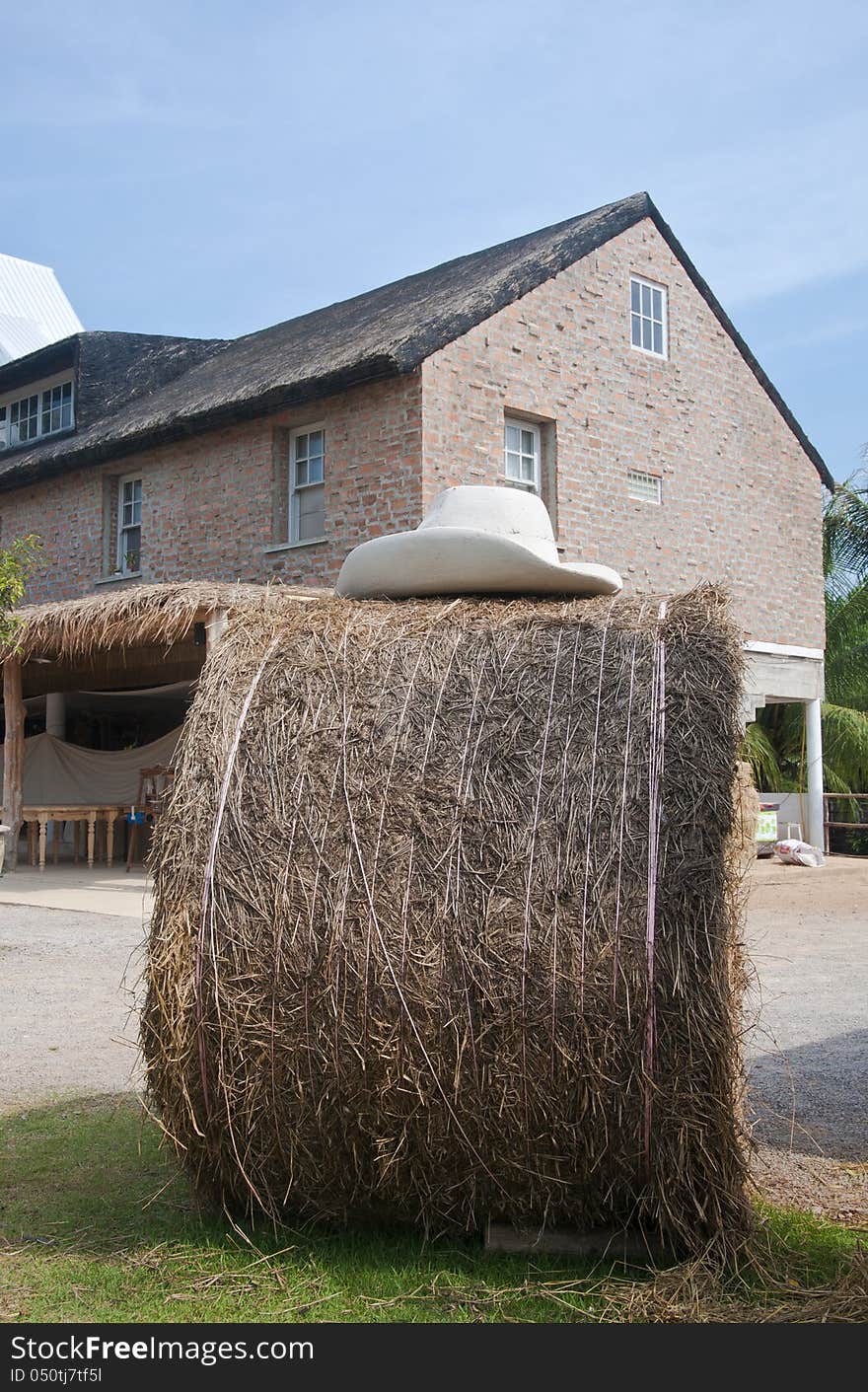 Straw Bale And Farmhouse In Background