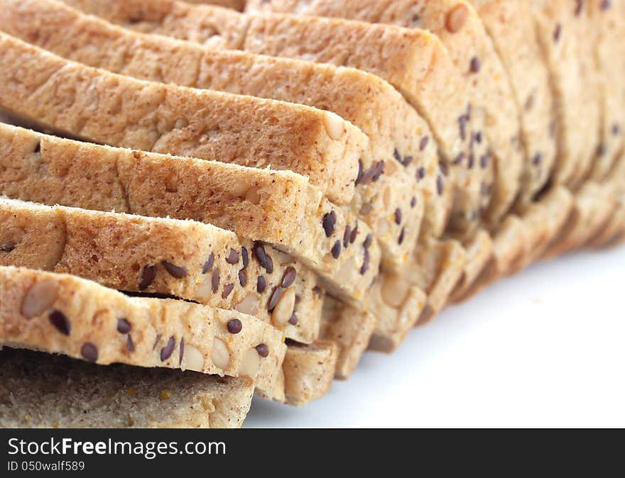 Closeup of multigrain bread slices with flaxseeds and pumpkin seeds on white background