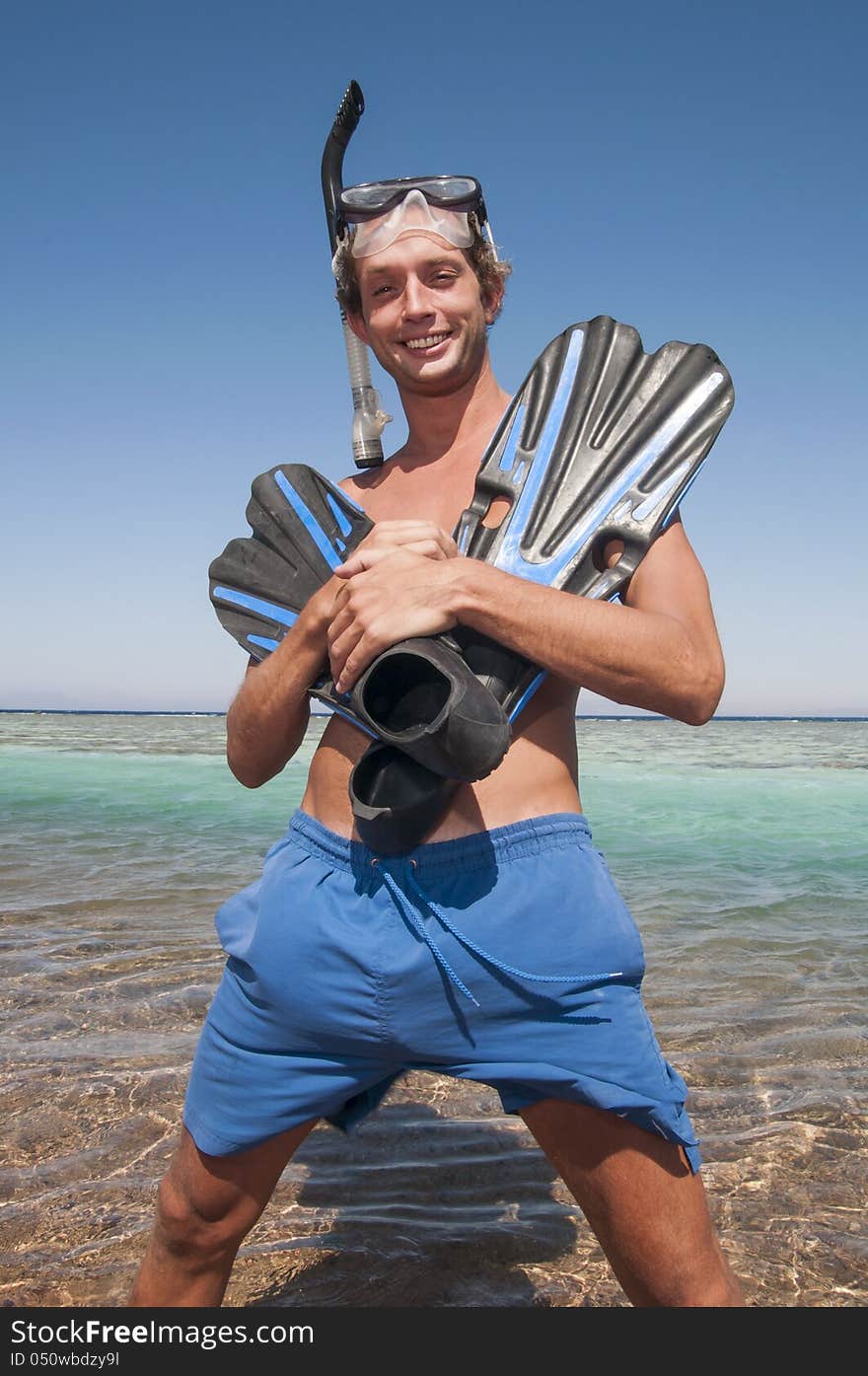 Man on a beach with mask and finns about to swim in ocean. Man on a beach with mask and finns about to swim in ocean