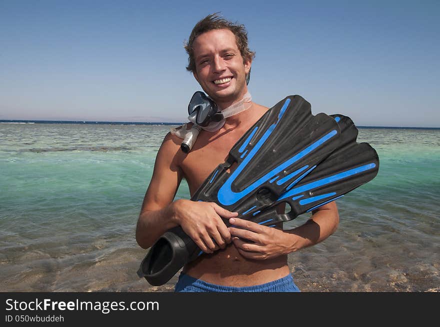 Man on a beach with mask and finns about to swim in ocean. Man on a beach with mask and finns about to swim in ocean