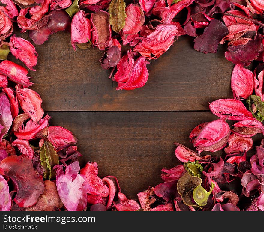 Flower Petals forming a heart shape against wooden background