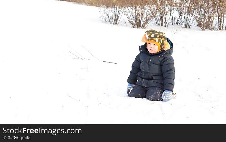 Cute little boy kneeling in winter snow