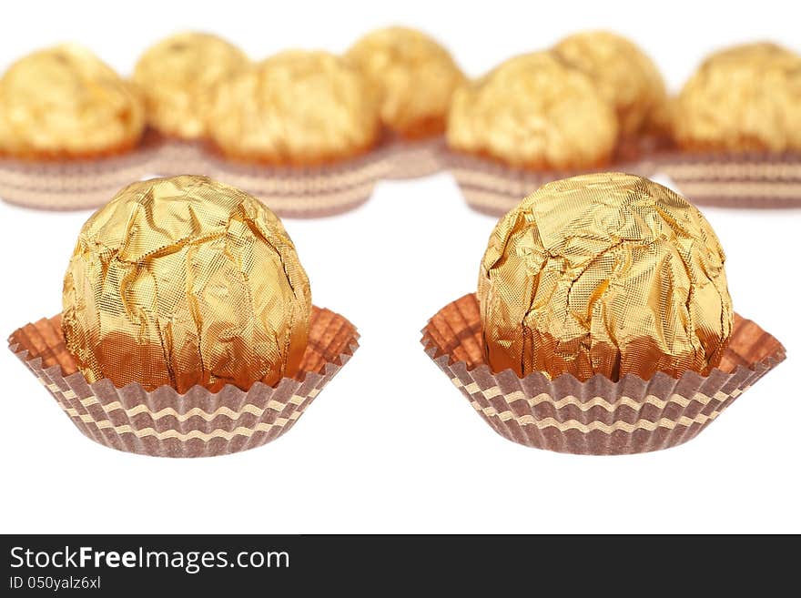 Group chocolate candies wrapped in gold. On a white background.