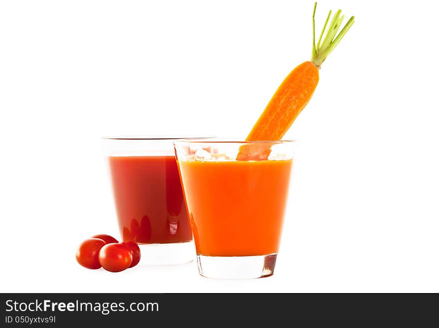 Two glasses of healthy freshly blended tomato and carrot juice accompanied by whole ripe tomatoes and a carrot isolated on white