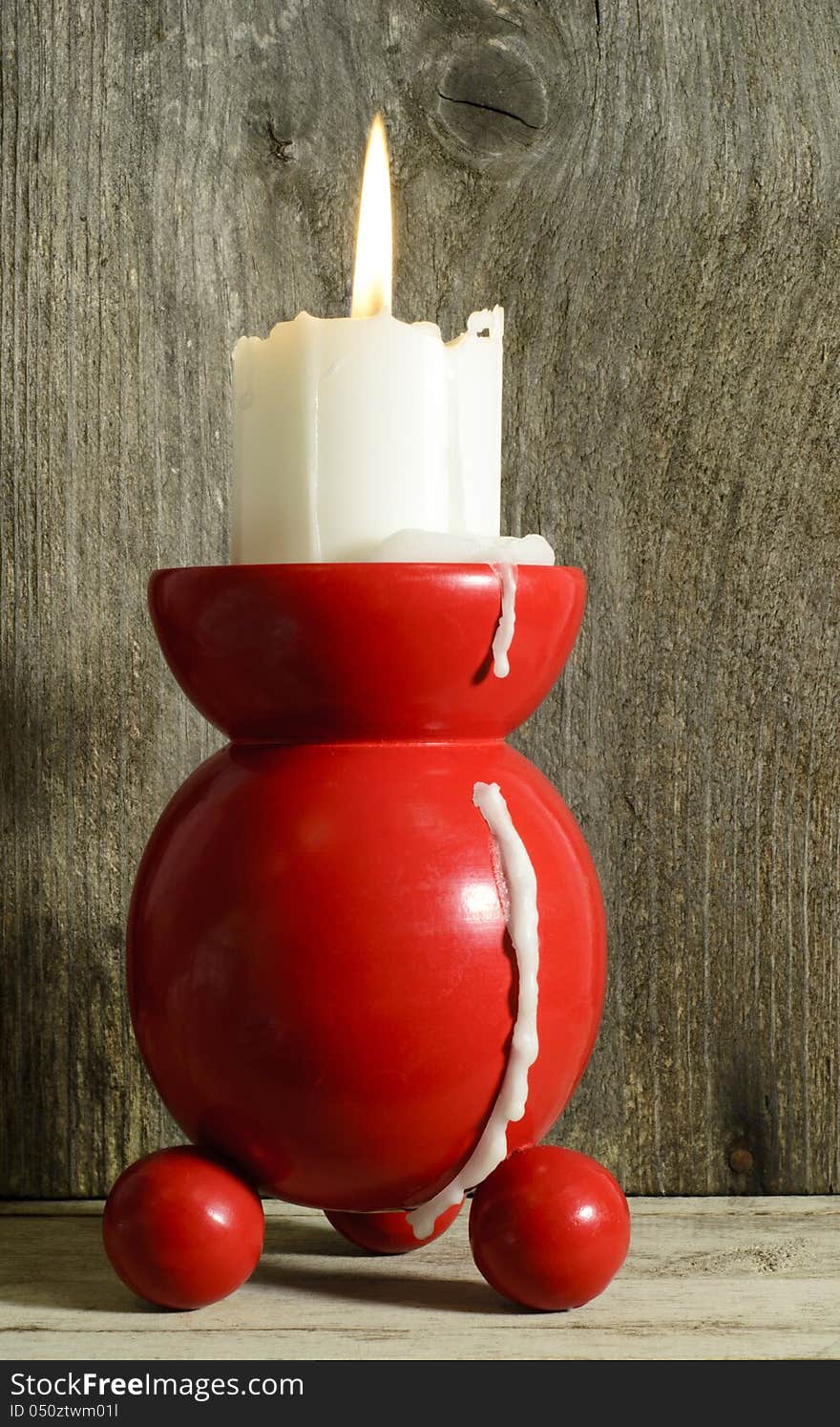 Red and round traditional candle holder with burning candle. Red and round traditional candle holder with burning candle