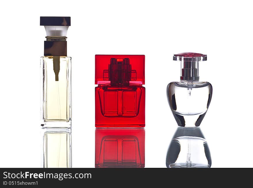 Three bottles of perfumes isolated on white and reflecting on a piece of glass. Three bottles of perfumes isolated on white and reflecting on a piece of glass.