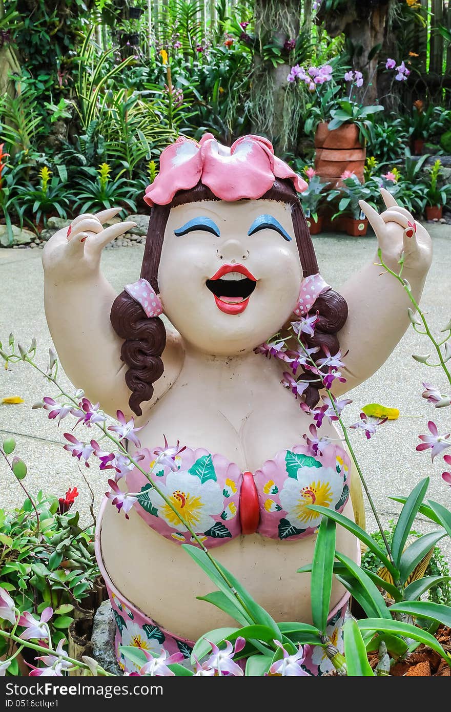 Beautiful fat lady sculpture with various orchids in garden, Thailand