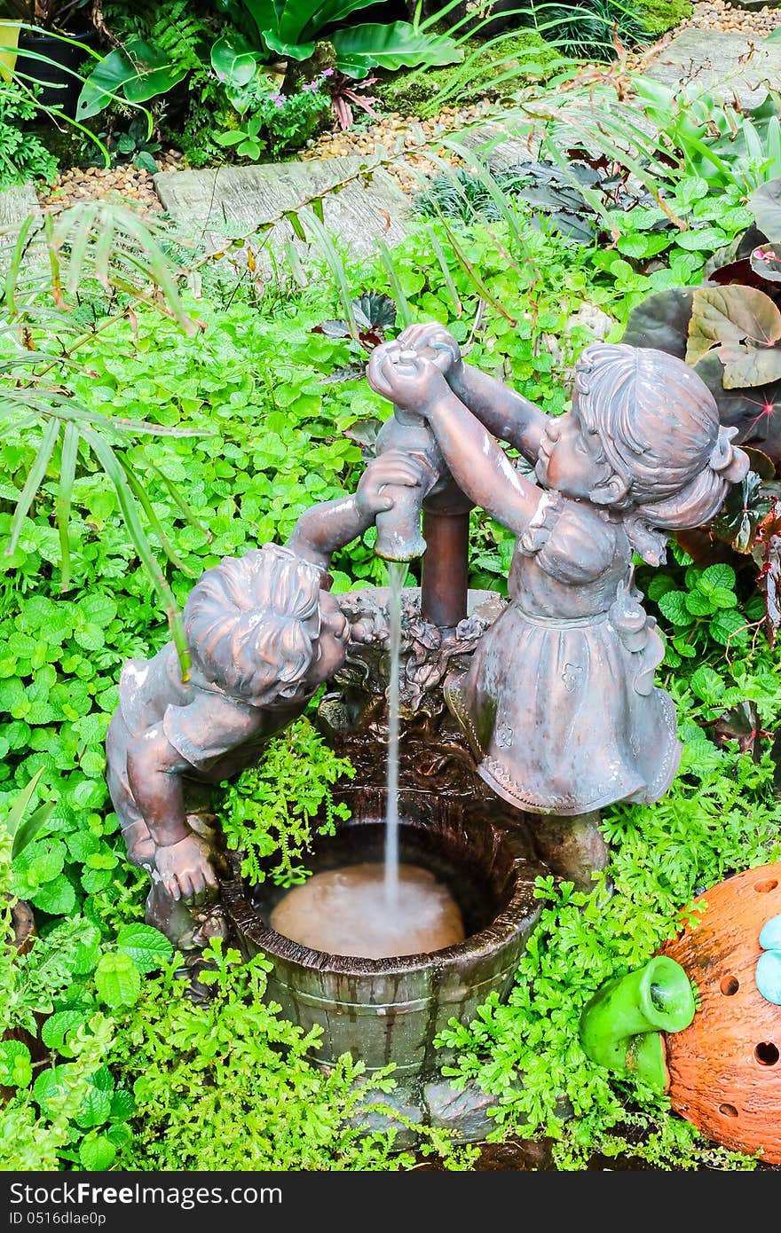 Boy and girl with well sculpture in botanic garden