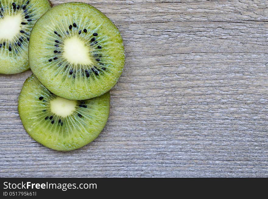 Fresh kiwi slices on wood texture .