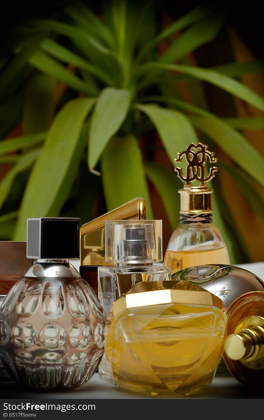 Different bottles of perfumes on green background.