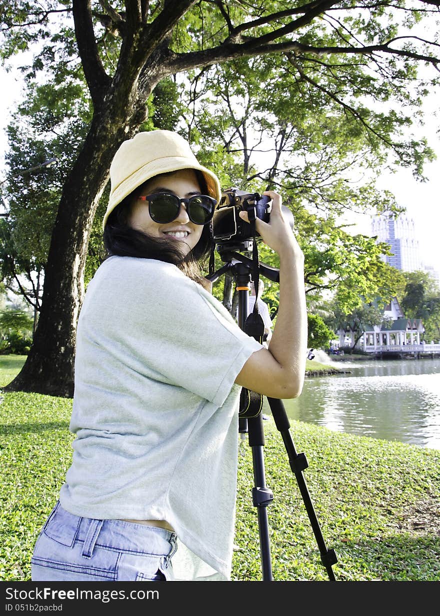 Beautiful smiling asian girl with camera on nature.