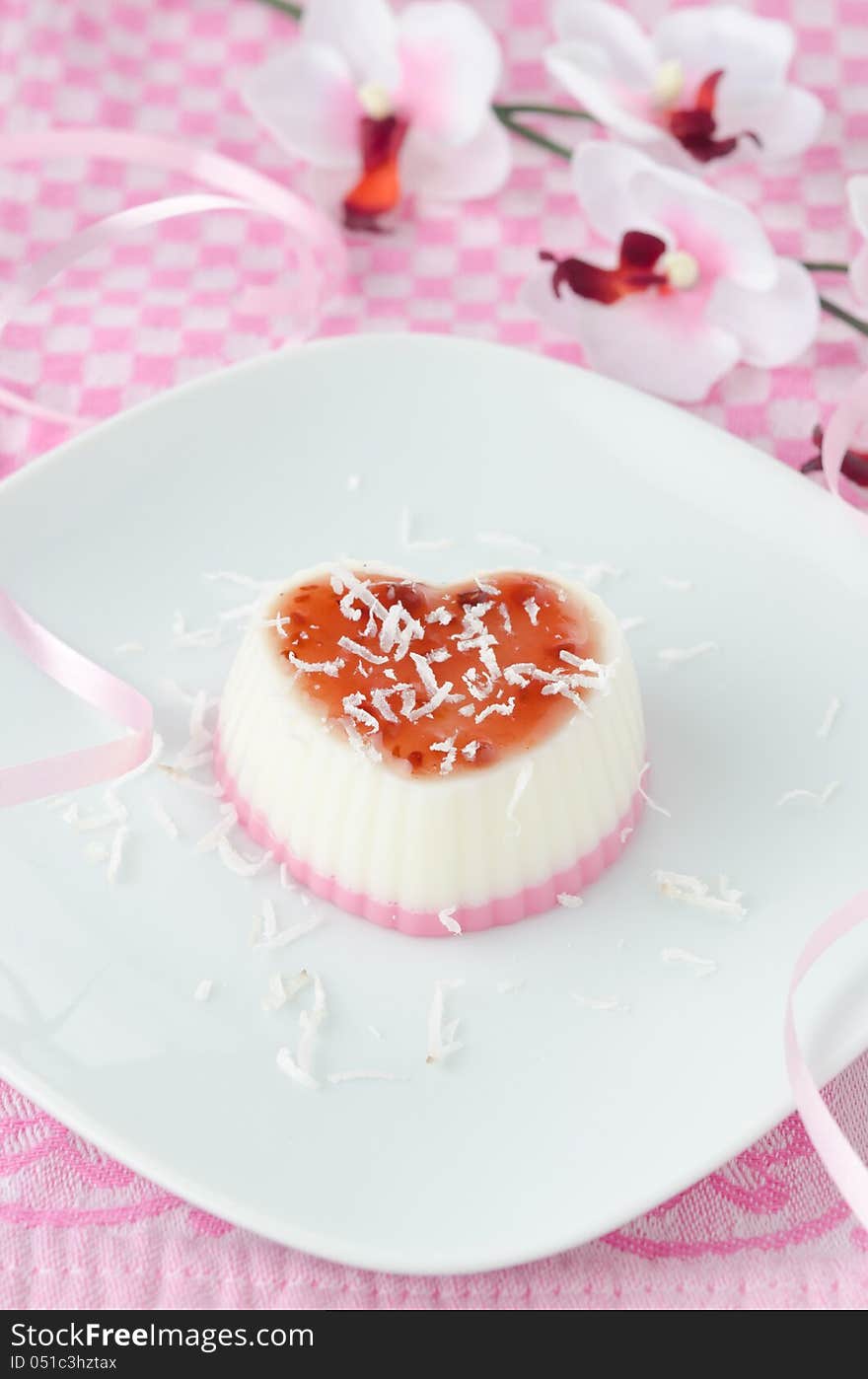 Two-layer dessert with coconut cream in the form of heart on white plate