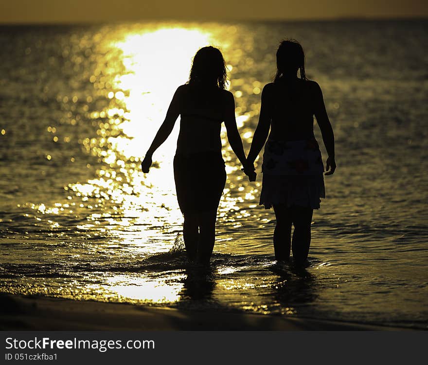 Two girls holding hands and going into the water. Two girls holding hands and going into the water