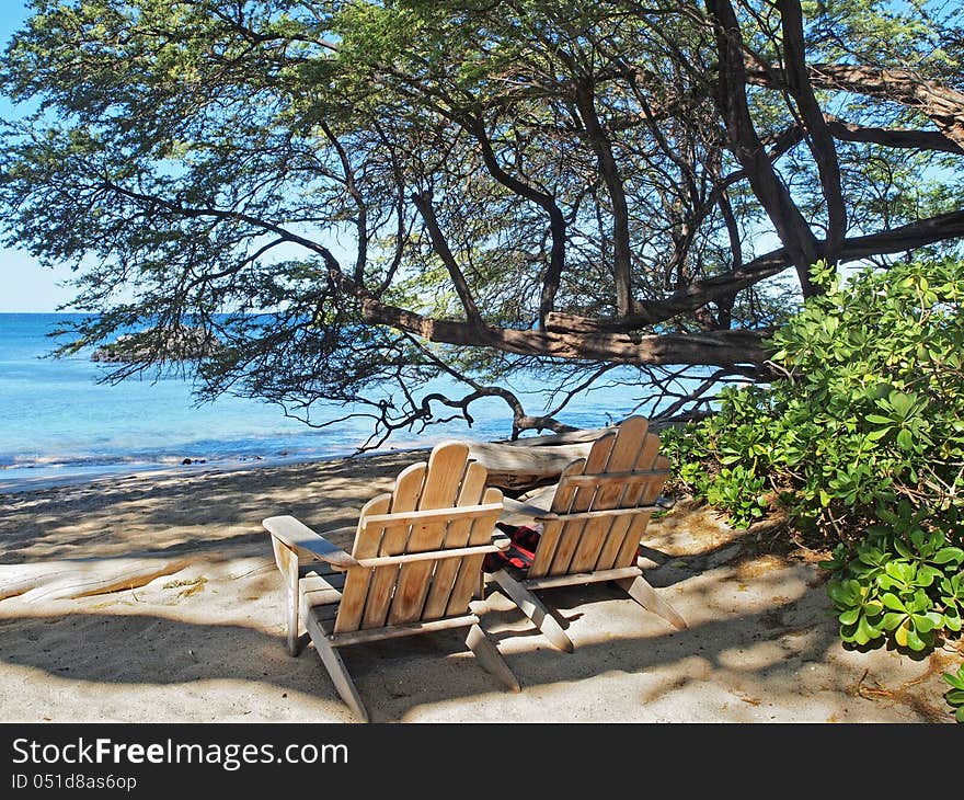 Two Wooden Adirondack  Chairs Overlooking Sandy Ocean Beach