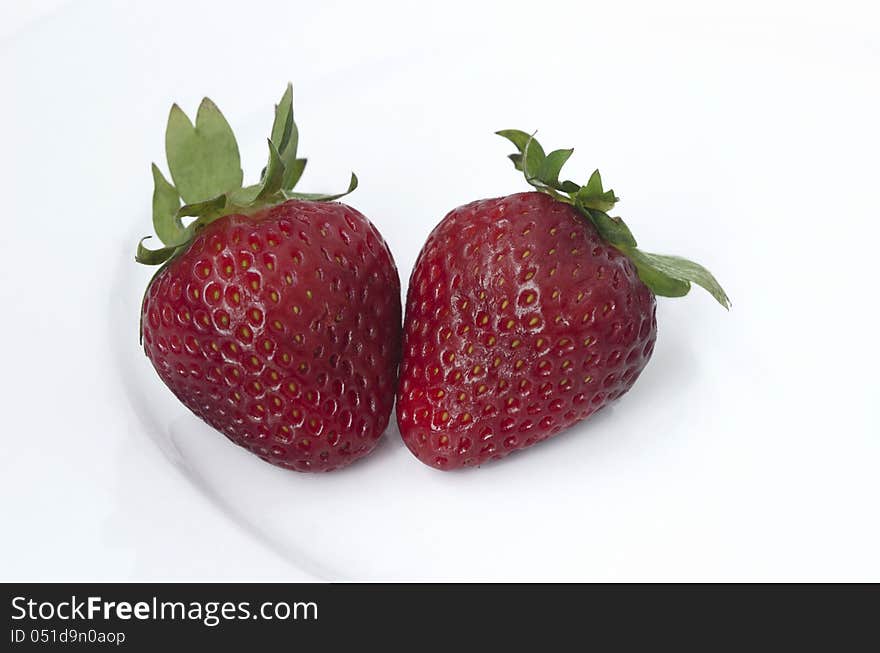 Two Strawberries on a white plate on a white background.