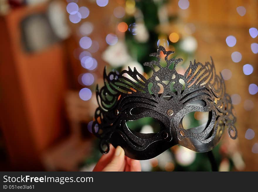 Close up a beautiful black New Year's mask against a fur-tree. Close up a beautiful black New Year's mask against a fur-tree