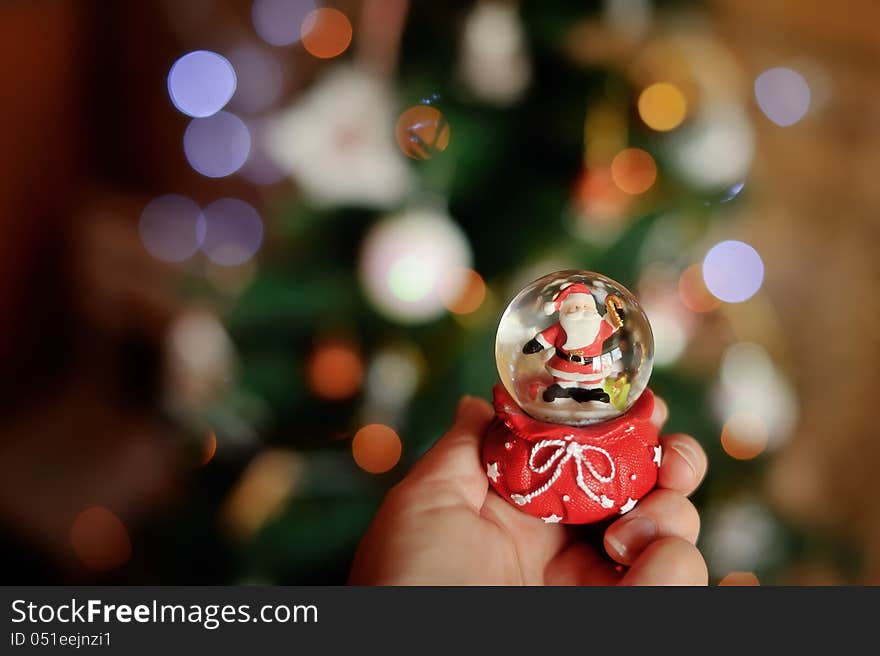 Against a New Year tree in a hand a sphere with Santa Claus. Against a New Year tree in a hand a sphere with Santa Claus