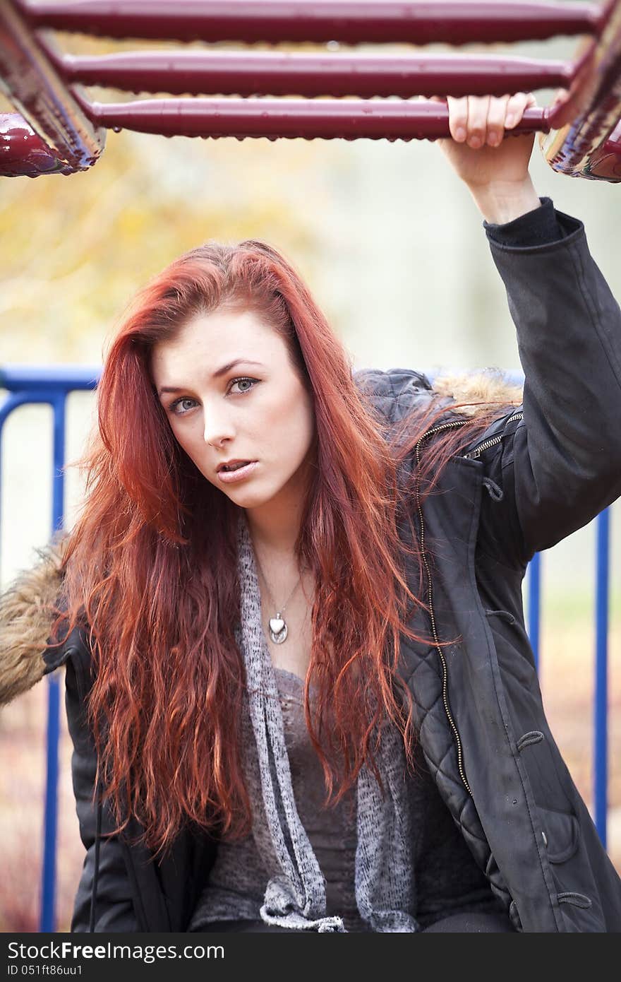 Young woman with beautiful red hair on playground equipment. Young woman with beautiful red hair on playground equipment.