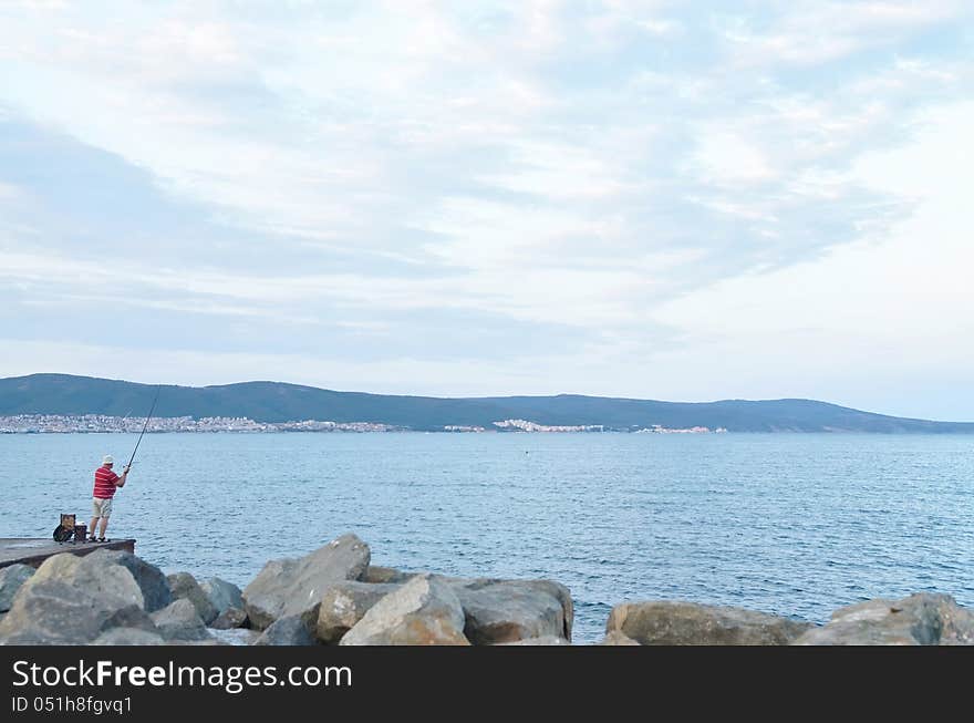 The picture of the fisher. He is angling at the sea. The picture of the fisher. He is angling at the sea.