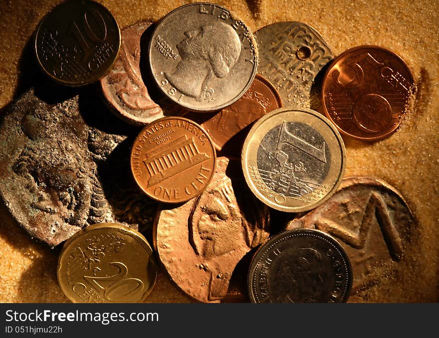 Business concept. Various modern and ancient coins on sand surface. Business concept. Various modern and ancient coins on sand surface