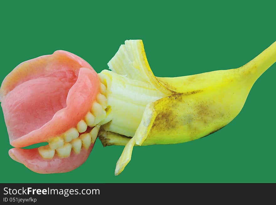 Banana sandwiched  artificial teeth photographed against a green background. Banana sandwiched  artificial teeth photographed against a green background